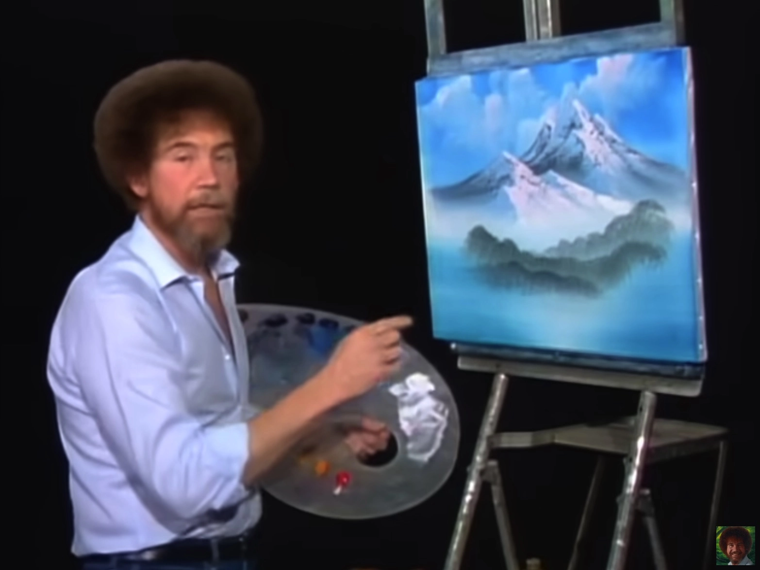 Bob Ross demonstrating the wet-on-wet oil painting technique to create a misty mountain landscape in his Joy of Painting series